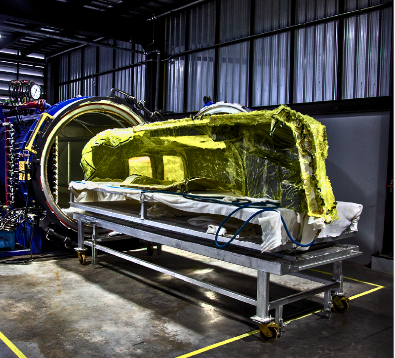 Vacuum-bagged carbon fiber part on the loading trolley in front of the autoclave